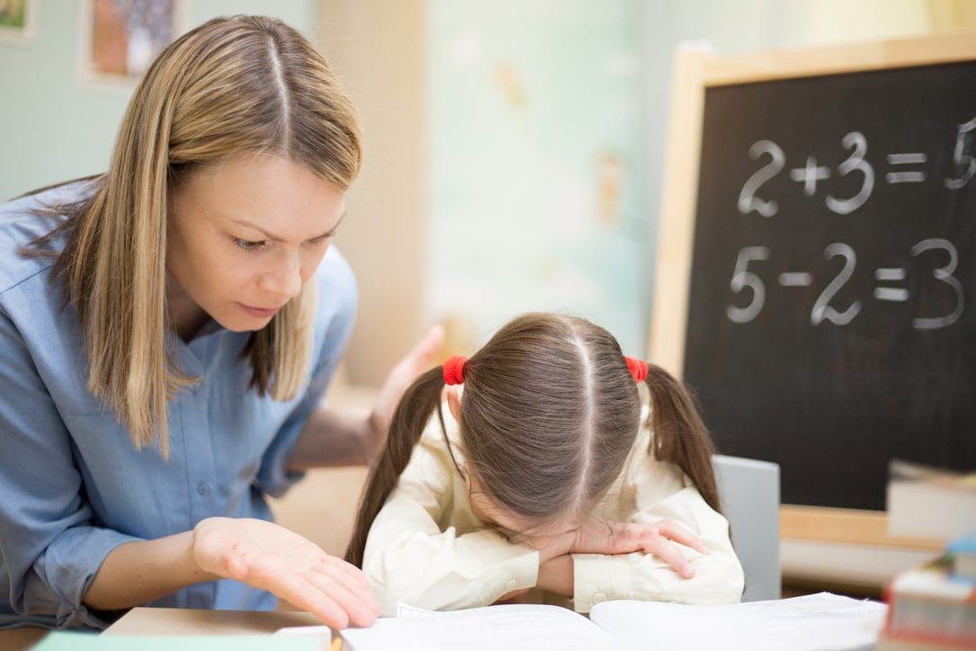 Mother Scolding Little Daughter Sulking on the Table with Homework